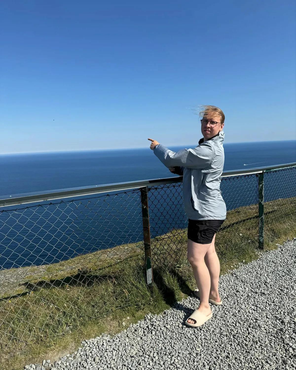 Sanni Ahola off the ice, pointing out to sea from a windy clifftop